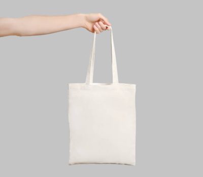 Male hand holding eco bag isolated on white background.